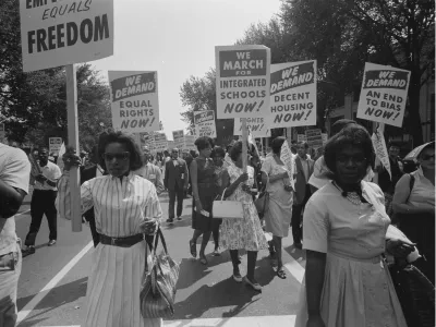 Mid-twentieth century civil rights marchers holding signs demanding freedom and equality